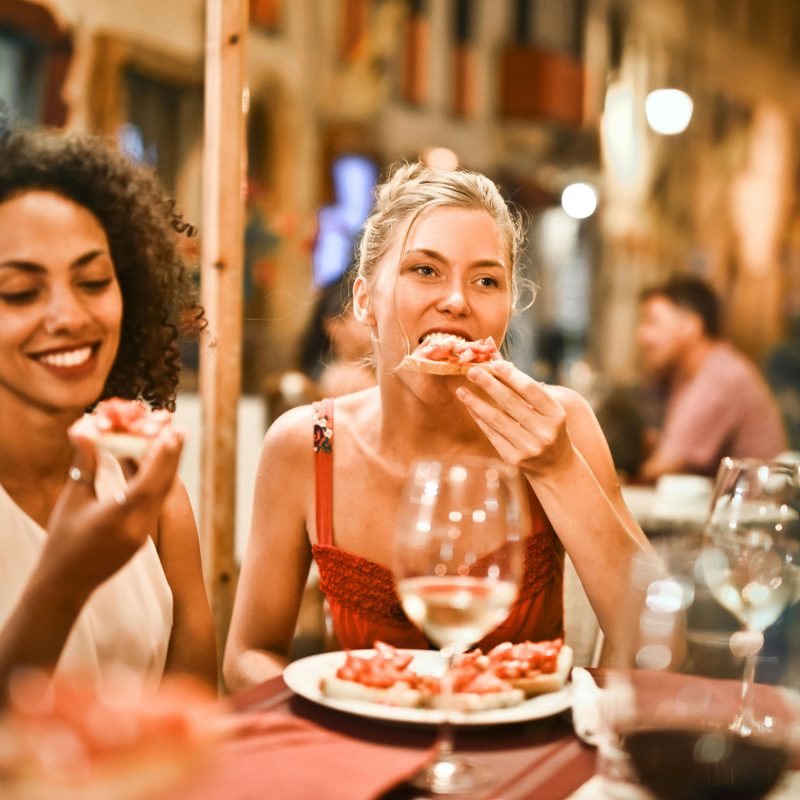 Two women eating pizza at restaurant