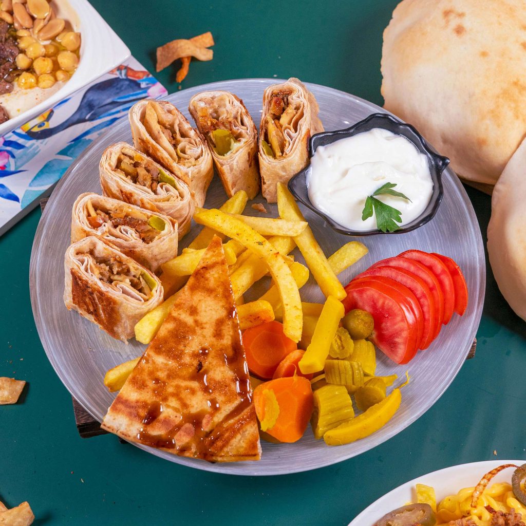 Plate with schwarma sandwich, fries, and vegetables